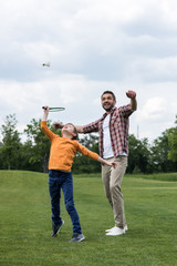 Smiling father teaching happy son playing badminton outdoors