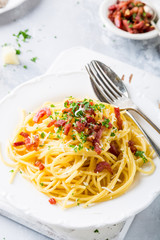 Italian pasta spaghetti Carbonara with fried bacon, parmesan cheese and parsley on white plate. Restaurant food concept.