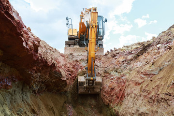 Excavator digging a pit. Bucket crashed into the ground.