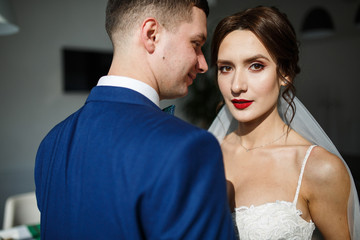 Bride looks over groom's shoulder standing in the hall
