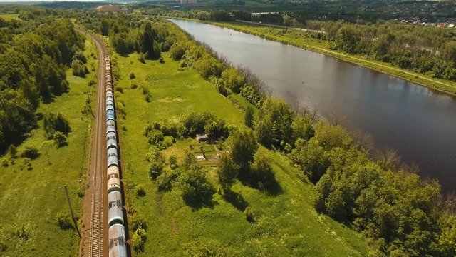 Freight train with cisterns and containers on the railway. Railway and highway with cars. Aerial view Container Freight Train, Locomotive in the countryside. 4K, flying video, aerial footage.