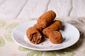Homemade healthy vegan chocolate truffles with dates, coconut flakes and rolled oats served on white plate