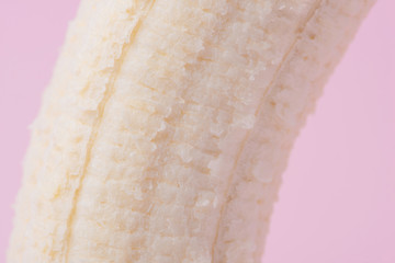 Detail of peeled banana on pink background