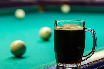 A mug with a dark beer on the billiard table. Table for Russian billiards
