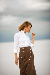 Young woman stands on sand in desert and smiles.