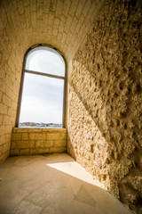 Obraz premium Window in old fortress with sunny harbor behind