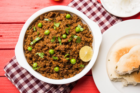 Indian Masala Kheema Pav or khima or Dry Spicy Minced Meat usually served with indian flat bread called kulcha/roti/chapati, garnished with green peas. Selective focus