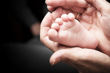 Baby's leg in the hands of parents