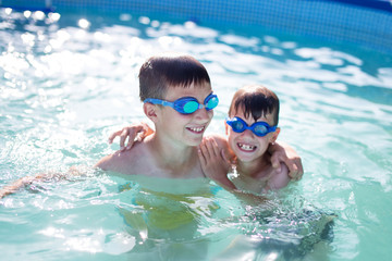Naklejka premium Happy little kids playing in swimming pool at summer