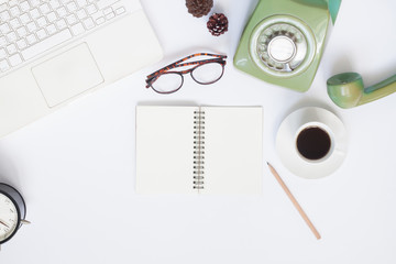 Creative flat lay of workspace with white laptop, retro style telephone, coffee cup and blank notebook for text