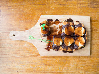 french toasts with banana chocolate sauce on wooden cutting board ,on wooden background