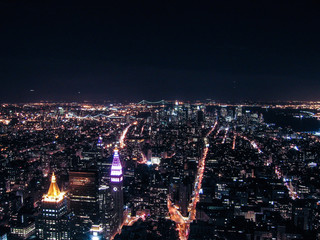 View of night cityscape or skyline of New York City with moon and illuminated buildings from Empire State Building