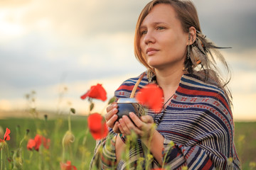Woman in poncho with calabash on flower field