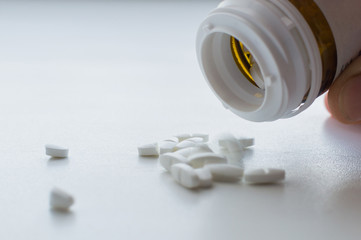 Oval pills spilling and dropped out of pill bottle