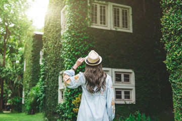 young woman holding hat with green nature background,travel in nature,vacation and relaxation concept.vintage tone and flare effect.