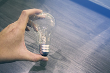 hand pick clear light bulb blue light background