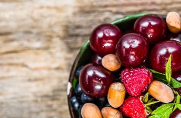 Various berry fruits in a bowl on wooden table