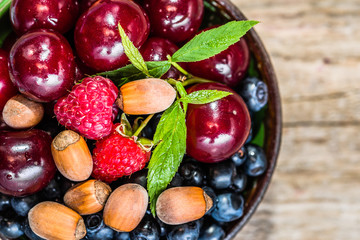 Various berry fruits in a bowl on wooden table