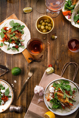 Tacos with fried avocados , tomatoes and greens on distressed wooden background. Served with beer, lime and olives. Mexican cuisine interpretation