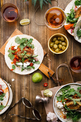 Tacos with fried avocados , tomatoes and greens on distressed wooden background. Served with beer, lime and olives. Mexican cuisine interpretation