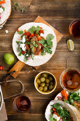 Tacos with fried avocados , tomatoes and greens on distressed wooden background. Served with beer, lime and olives. Mexican cuisine interpretation