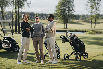 multiethnic golfers with golf clubs talking and spending time together on golf course