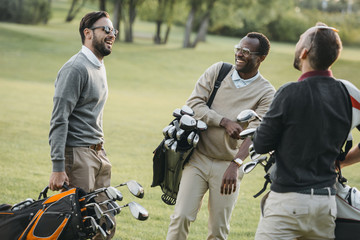 Multiethnic golf players with golf clubs having fun on golf course - obrazy, fototapety, plakaty