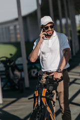 smiling golf player talking on smartphone before golf game