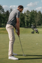 Fototapeta premium young casual man playing golf on green at daytime