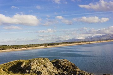 Fototapeta na wymiar Scenic coastal vista looking eastwards across Llanddwyn Bay towards the snow-capped Snowdonia Mountain Range, Llanddwyn Island, Anglesey, North Wales