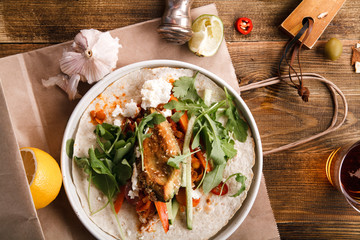 Tacos with fried avocados , tomatoes and greens on distressed wooden background. Served with beer, lime and olives. Mexican cuisine interpretation