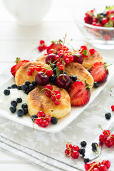 Healthy breakfast: cheese pancakes with sour cream and fresh ripe berries on white wooden table. Selective focus 