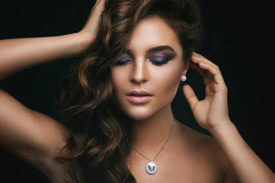 Woman with curly hair, beautiful make-up and expensive pendant with a dimond