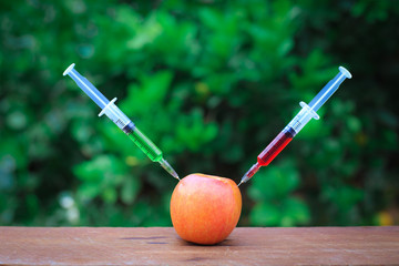 Needle and syringe injected in the apple, Enhanced fruits. Nutrition concept, GMO concept....