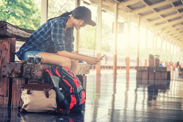 Fototapeta premium samotnie kobieta siedzi i gra inteligentny telefon z akcesoria podróżne, akcesoria podróżne i koncepcja backpacker, efekt flary słońca i ton vintage.
