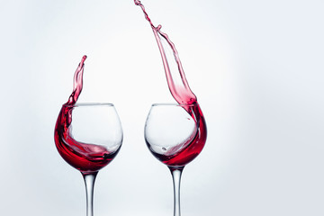 Two wine glasses in toasting gesture with big splashing.