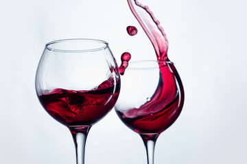 Two wine glasses in toasting gesture with big splashing.