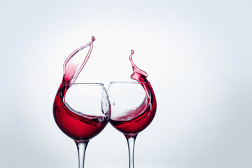 Two wine glasses in toasting gesture with big splashing.