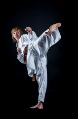 Crédence de cuisine en verre imprimé Arts martiaux Young athlete in a kimono on a dark background