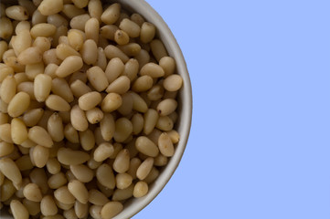 Bowl of pine nuts on a blue background
