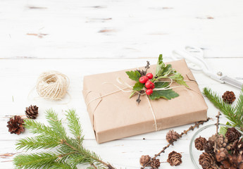 Wrapped gift in plain paper with a sprig of Holly and fir cones