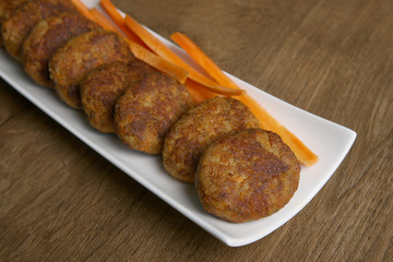 Fish cutlets with carrots. Homemade fried  cutlets in plate on wooden table.