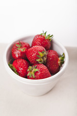 Strawberries in white bowl. Vertical composition with copy space. Summer natural beauty concept.