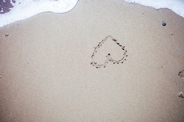 heart handwritten in sand at the beach