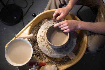 Hands of sculpture artist works on pottery wheel with clay