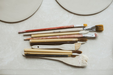 Fototapeta premium Top view on different rustic brushes with wooden holders for ceramic and workpieces for handmade plates