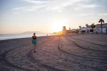 girl walking into sunset on a lonely beach in spain