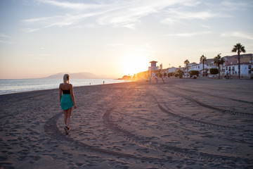 girl walking into sunset on a lonely beach in spain