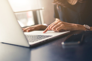 woman working on laptop,business office desk,using laptop computer technology on table for searching and planing successful concept,vintage tone and day light flare.
