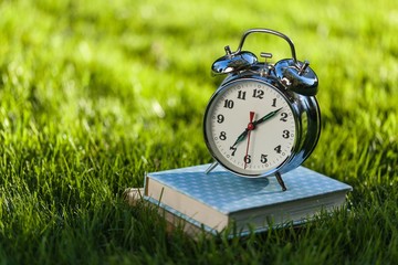 Clock and book on grass.